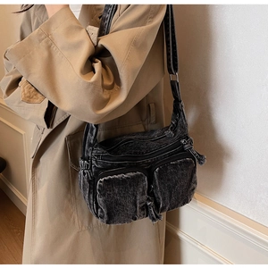 Black denim crossbody bag with multi-pocket design and fringe zipper on model