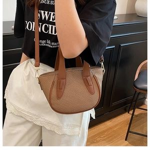 Detail showing the brown woven crossbody bag with leather straps and gold metal hardware