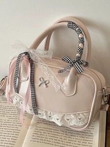 Pink patent leather Boston bag with silver bow accent and lace trim on vintage book