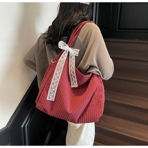Detail of red checkered tote bag with large white lace bow and spacious canvas interior