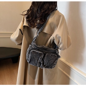 Detail of dark grey vintage denim crossbody bag with multi-pocket design on trench coat