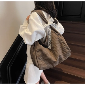 Brown checkered tote bag with a white lace bow detail shown on a female model