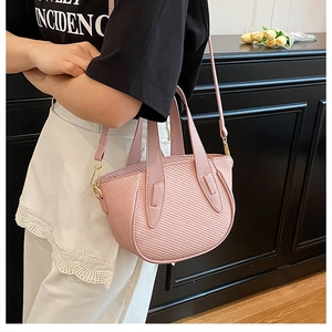 Detail view of pink textured leather bucket bag with top handles and adjustable strap