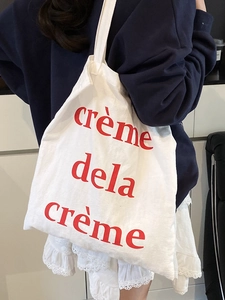 Sac fourre-tout en toile blanche avec imprimé rouge crème de la crème porté par mannequin