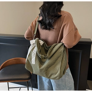 Detail of green plaid tote bag with white lace trim and adjustable nylon shoulder strap