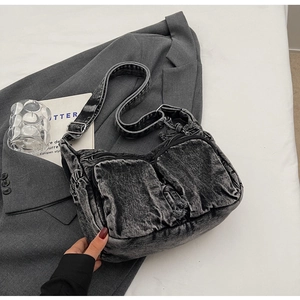 Detail of grey washed denim crossbody bag with multiple zip pockets on a blazer