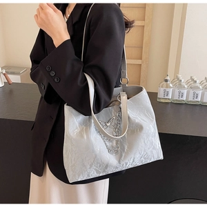Detail of silver wavy tote bag with metallic butterfly charm and chain strap