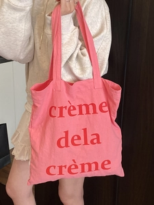 Sac fourre-tout en toile rose avec imprimé rouge porté par un mannequin en tenue décontractée