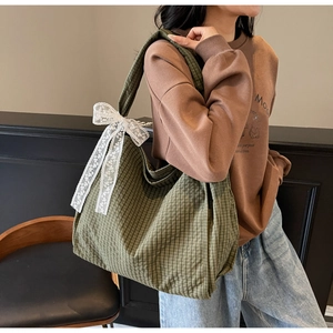 Detail of green plaid canvas tote bag with delicate white lace bow decoration