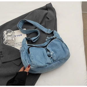 Detailed macro view of vintage blue denim crossbody bag with multiple zip pockets
