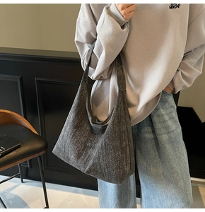 Close-up of a large grey denim hobo bag with grainy texture and wide shoulder strap