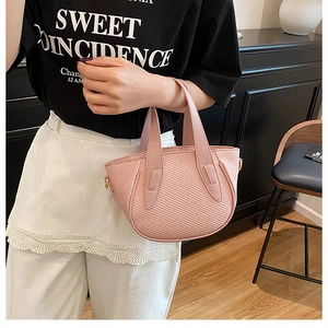 Detail of pink woven texture bucket bag with gold D-rings and flat top handle