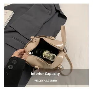 Macro shot showing internal capacity of cream patent leather Boston bag with perfume