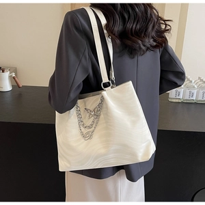 Detail of white wave texture tote bag with silver chains and butterfly pendant