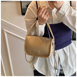 Detail of trendy milk tea crossbody bag with silver chain strap shown on model's shoulder