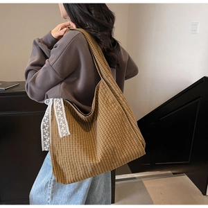 Close-up of lightweight canvas tote bag featuring classic brown plaid and white lace ribbons