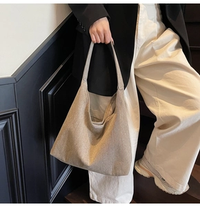 Detailed view of a spacious taupe canvas tote bag styled with a minimalist outfit