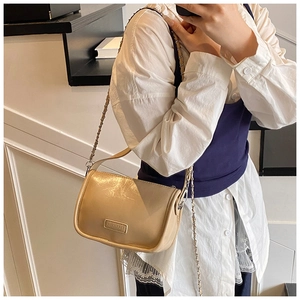 Detail of beige pillow bag with glossy finish and chain leather shoulder strap