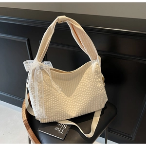 Detailed texture of off-white waffle fabric bag with delicate lace bow accent