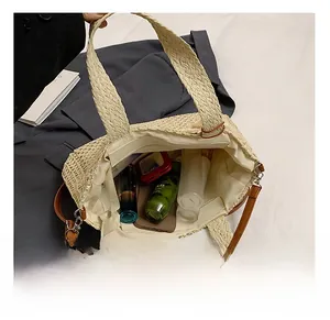 Vue macro de l'intérieur spacieux de ce sac bandoulière en paille tressée de couleur beige