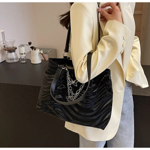 Close-up of black tote bag featuring wave textures, silver chains, and butterfly charm