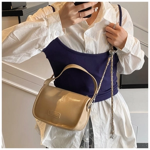 Detail view of glossy cream faux leather pillow bag with stylish gold chain strap