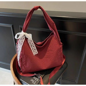 Detail view of red checkered canvas tote with white lace bow on a vintage black chair
