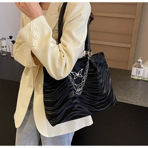 Detail of black tote bag featuring wave textures, silver butterfly and metal chains