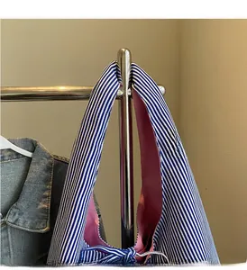Detail of blue striped tote bag featuring pink lining and durable reinforced handles