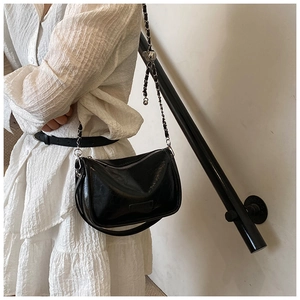 Detailed view of a black chic pillow bag with metallic chain strap worn on the shoulder