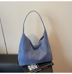 Macro shot of dark blue denim hobo bag with washed texture and seamless shoulder strap