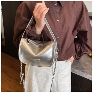 Detailed macro view of the silver metallic pillow bag with chain and brand tag