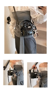 Detail view of black glossy patent leather Boston bag with pearl chain and doll charms