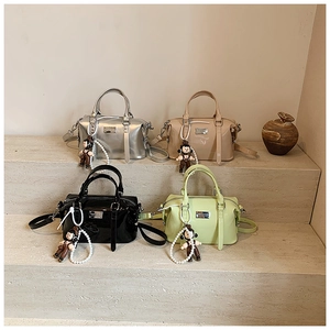 Detail view of colorful glossy patent leather Boston bags with pearl chains and doll charms