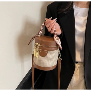 Detail of woven cylinder bag featuring contrast leather trim and decorative silk scarf handle