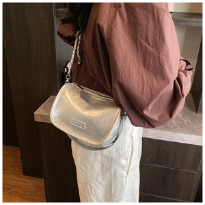 Close-up of metallic silver pillow bag with chain strap on model's shoulder