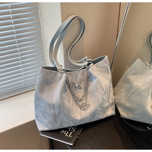 Detailed macro view of the wavy pleated texture and silver butterfly chain on the blue tote bag