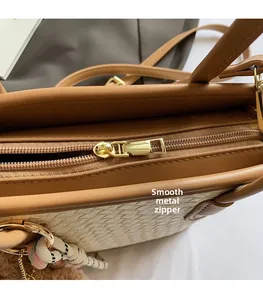 Detailed close-up of hardware zipper pull and woven texture on brown leather handbag