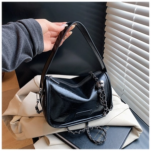 Detailed view of black wrinkled PU leather pillow bag with metal chain and wide handle