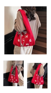 Detail of red canvas tote bag with white letters and a striped bow on stairs