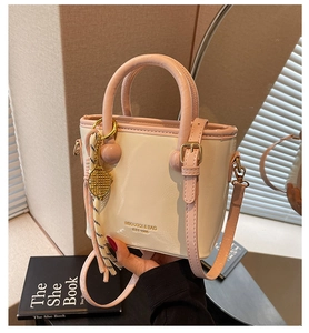 Détail du sac seau crème avec anses roses, logo doré et accessoire de charme raquette de tennis
