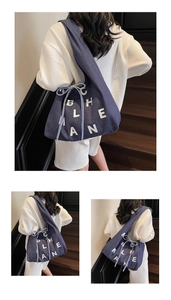 Detail of dark blue denim tote bag with white BHLEAN lettering and ribbon bow