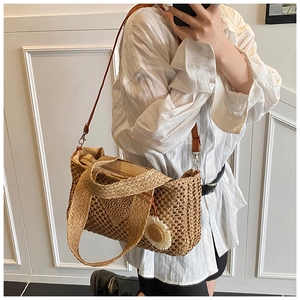 Détail d'un sac cabas en paille tissé à la main avec breloque marguerite et cuir brun