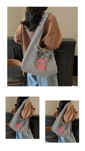 Detail of striped canvas tote with red lettering and decorative bow drawstring closure