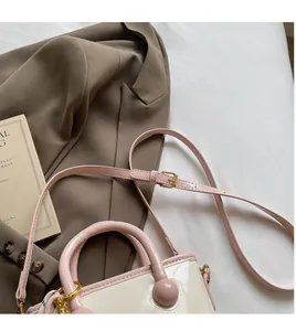 Détail de la bandoulière réglable et du sac seau crème brillant avec bord rose