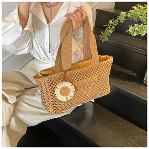 Détail du sac à main en paille avec texture tissée et pendentif marguerite blanche