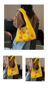 Detailed macro of the bright yellow canvas tote bag showing the bold red letter print design