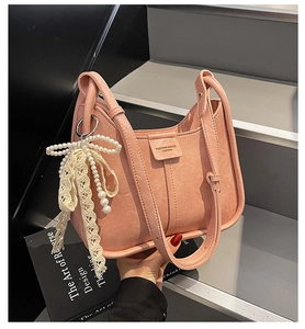 Close-up of pink lychee grain leather handbag featuring pearl bow lace charm and silver hardware