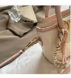 Détail du sac seau verni crème avec boucles dorées et breloque en corde tressée chic