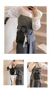 Détail d'un sac seau noir brillant avec charme de gland tissé et bandoulière amovible
